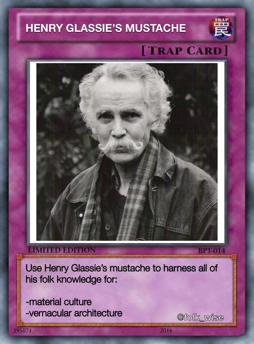 Image of a reddish-purple Yu-Gi-Oh Trap Card. In the center of the card is a black and white photo of Henry Glassie, an older white man in a leather jacket and flannel, with a large mustache curled at the ends. Text at the top of the card reads “Henry Glassie’s Mustache [Trap Card]” and underneath the photo, text reads “Limited Edition: Use Henry Glassie’s mustache to harness all of his folk knowledge for: - Material Culture - Vernacular Architecture.”